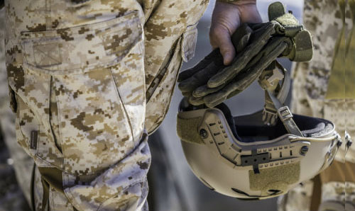 Military personnel holding a combat helmet
