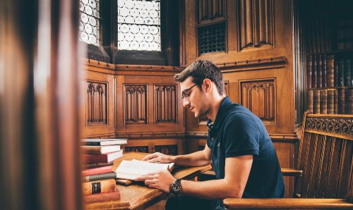 A male student reading a book in the Library 