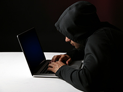 Young man in hood on a laptop