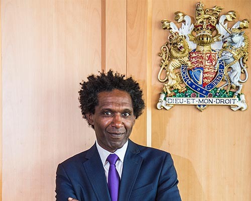 Lemn Sissay in front of the crest in the moot room.