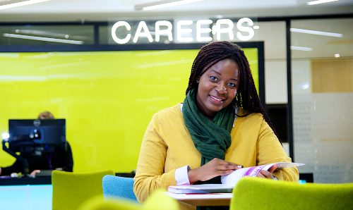 A female student sat in front of the 'Careers' sign 