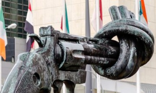 A statue of a gun alongside flags