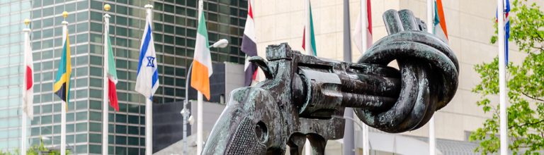 A statue of a gun alongside flags