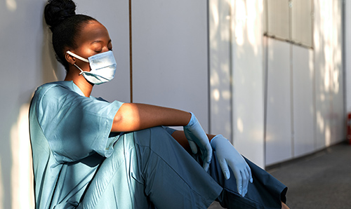 Exhausted nurse sat wearing PPE