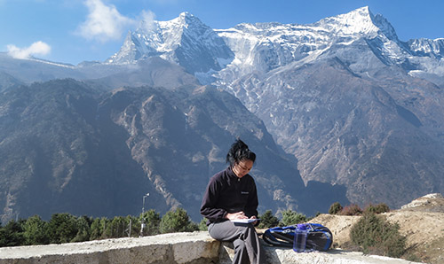 Person sat making notes with mountains in the background