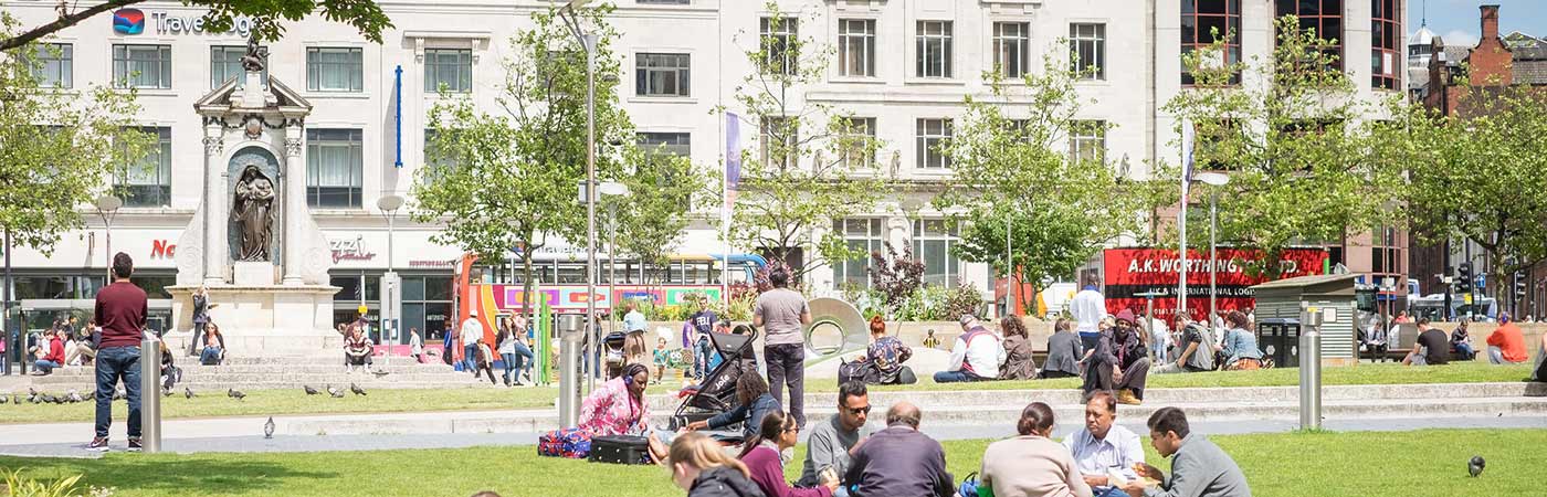 People sat in Manchester Piccadilly Gardens