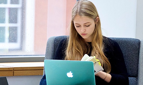 Female student reading information in front of laptop