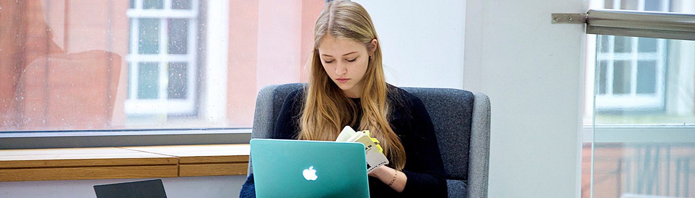Female student reading information in front of laptop