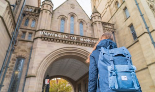 UG student looking up at The University of Manchester sign 